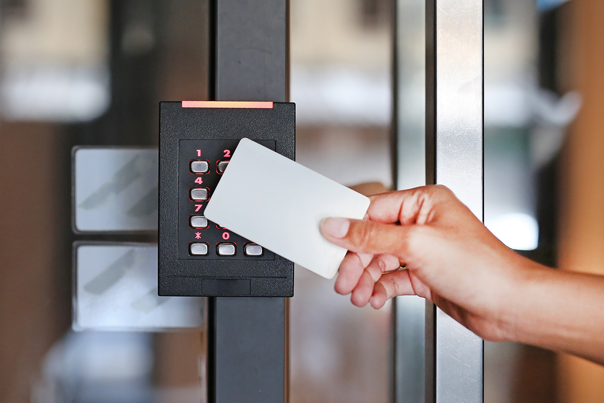 A door access control system. An office worker is scanning an entry card reader to access a secured building.